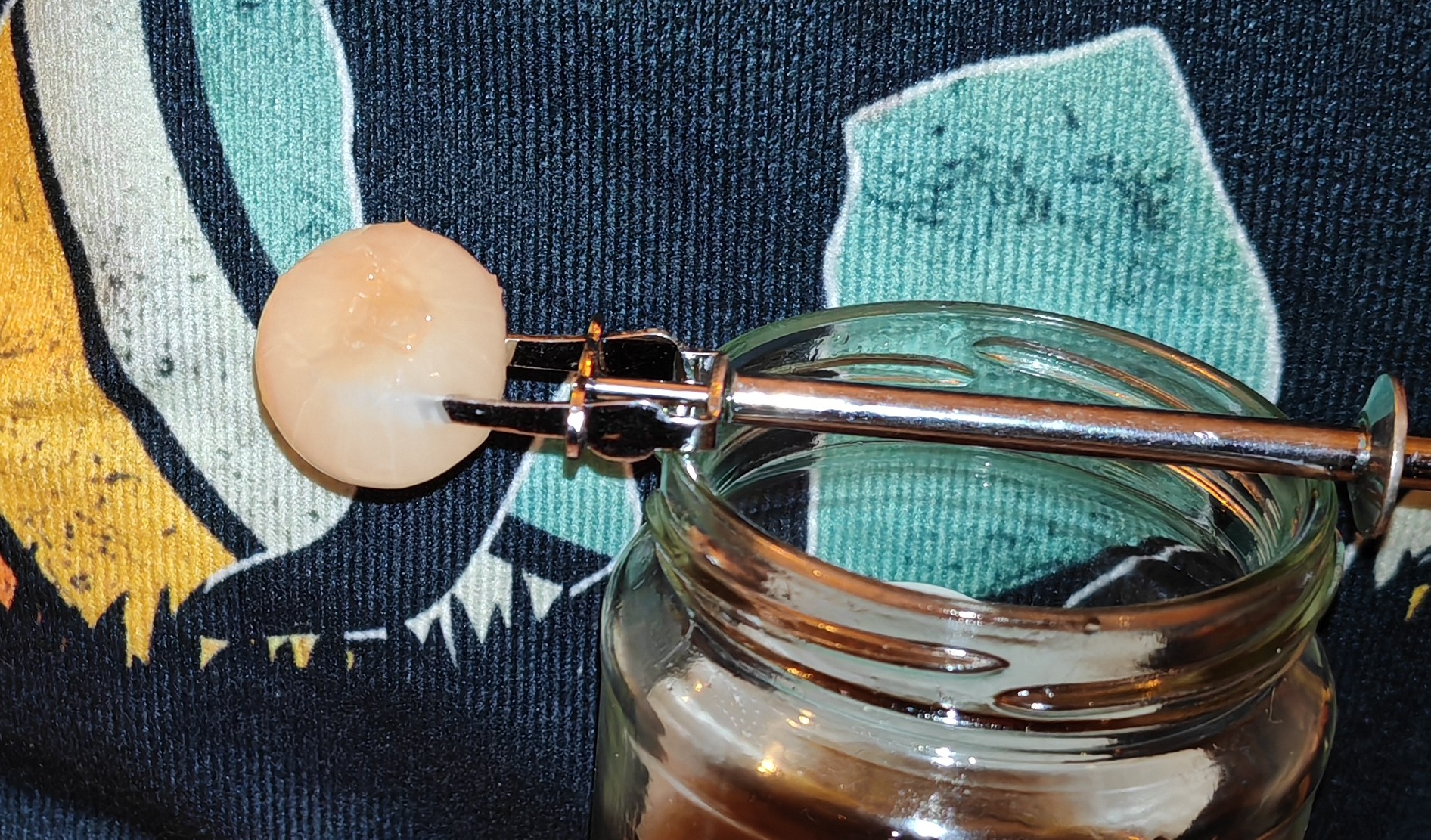 A single pale silverskin onion sits speared on a small silver pickle fork, ready for tasting. The onion has that translucent quality you want to see - suggesting it's been properly pickled through, though only the actual taste will reveal whether Sarson's has achieved the right balance.