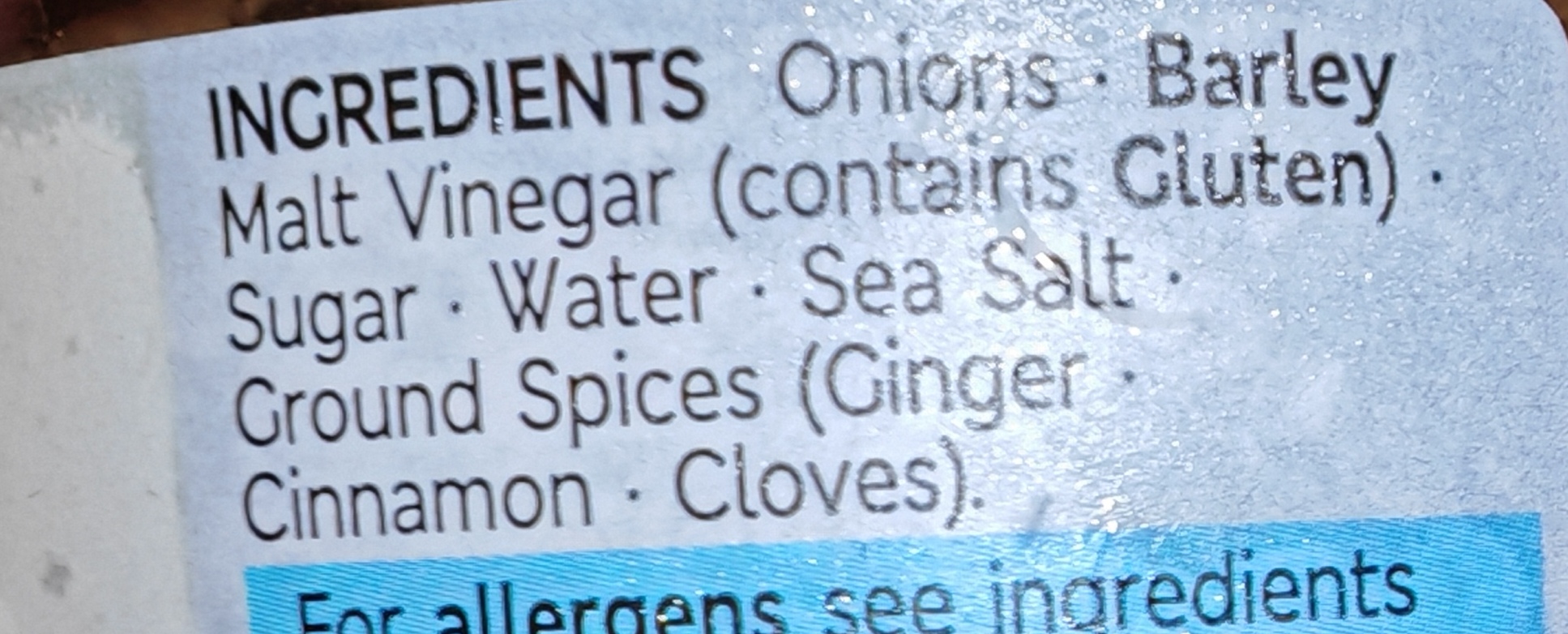 Close-up of the ingredients list on the jar's label, showing onions, barley malt vinegar (contains gluten), sugar, water, sea salt, and ground spices including ginger, cinnamon, and cloves.