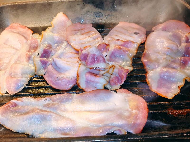 Photo: Bacon rashers laid out and cooking on a grill pan, before their transformation into proper breakfast material.