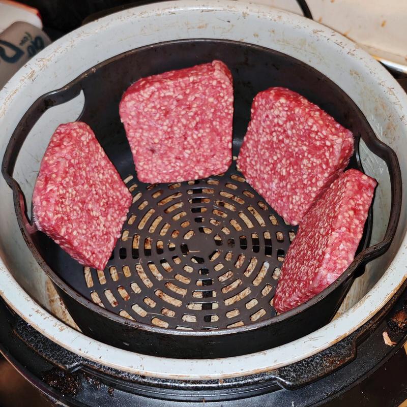 Photo: Five square Lorne sausage slices arranged in a circular air fryer basket, raw and ready for cooking. The geometric precision of Scottish breakfast engineering.