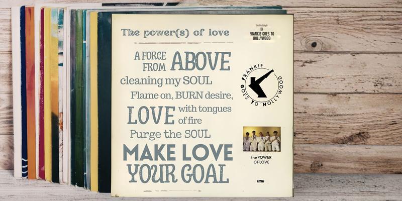A distressed 12-inch vinyl single sleeve for Frankie Goes To Hollywood's "The Power of Love" leans against a stack of records on a wooden surface. The cream sleeve features mixed-size typographic lyrics — "The power(s) of love / A force from above / cleaning my SOUL / Flame on, BURN desire / LOVE with tongues of fire / Purge theSOUL / MAKE LOVE YOUR GOAL" — alongside the band's logo, a small band photograph, and ZTT Records branding.