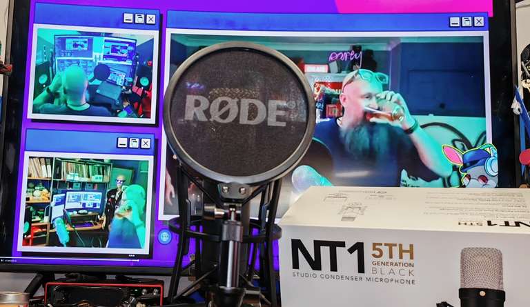 The same Røde NT1, now fitted with a pop filter bearing the Røde logo, suggesting someone intends to actually use it rather than just photograph it. The monitor behind shows the stream in full swing, including a graffiti-style 'theaardvark's radio show' graphic. Yamaha studio monitors flank the scene. The Red Focusrite interface is visible on the desk, quietly doing its job without demanding a photoshoot.